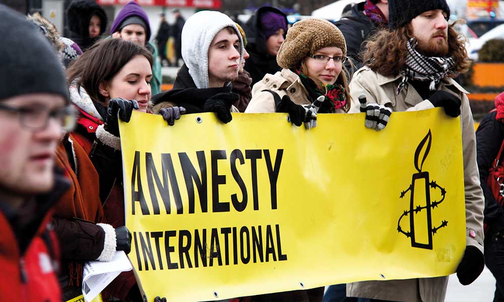 Manifestantes carregam cartaz da Amnesty International.